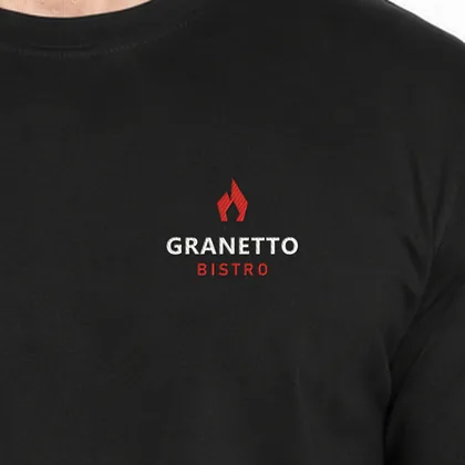 Zbliżenie haftu przykładowego logo bistro GRANETTO na czarnej koszulce — czerwona i biała nić (logo wymyślone, zdjęcie poglądowe)